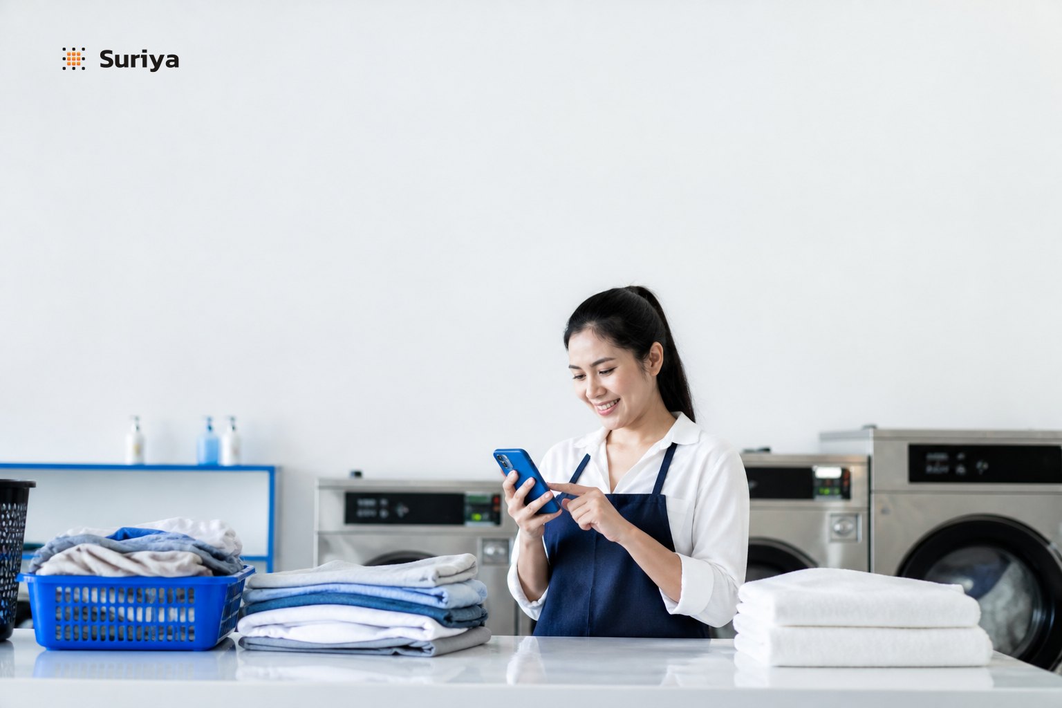 Owner of a Thai laundry shop reviewing AI agent pickup bookings and ready-to-collect alerts on a smartphone next to neatly folded clothes